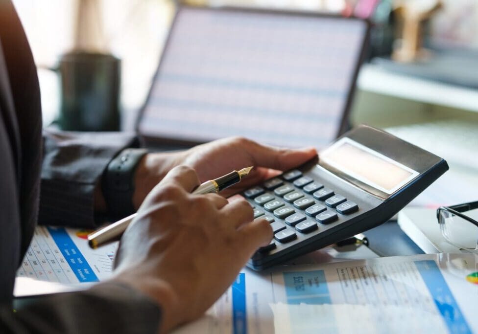 Person using calculator and reviewing financial documents